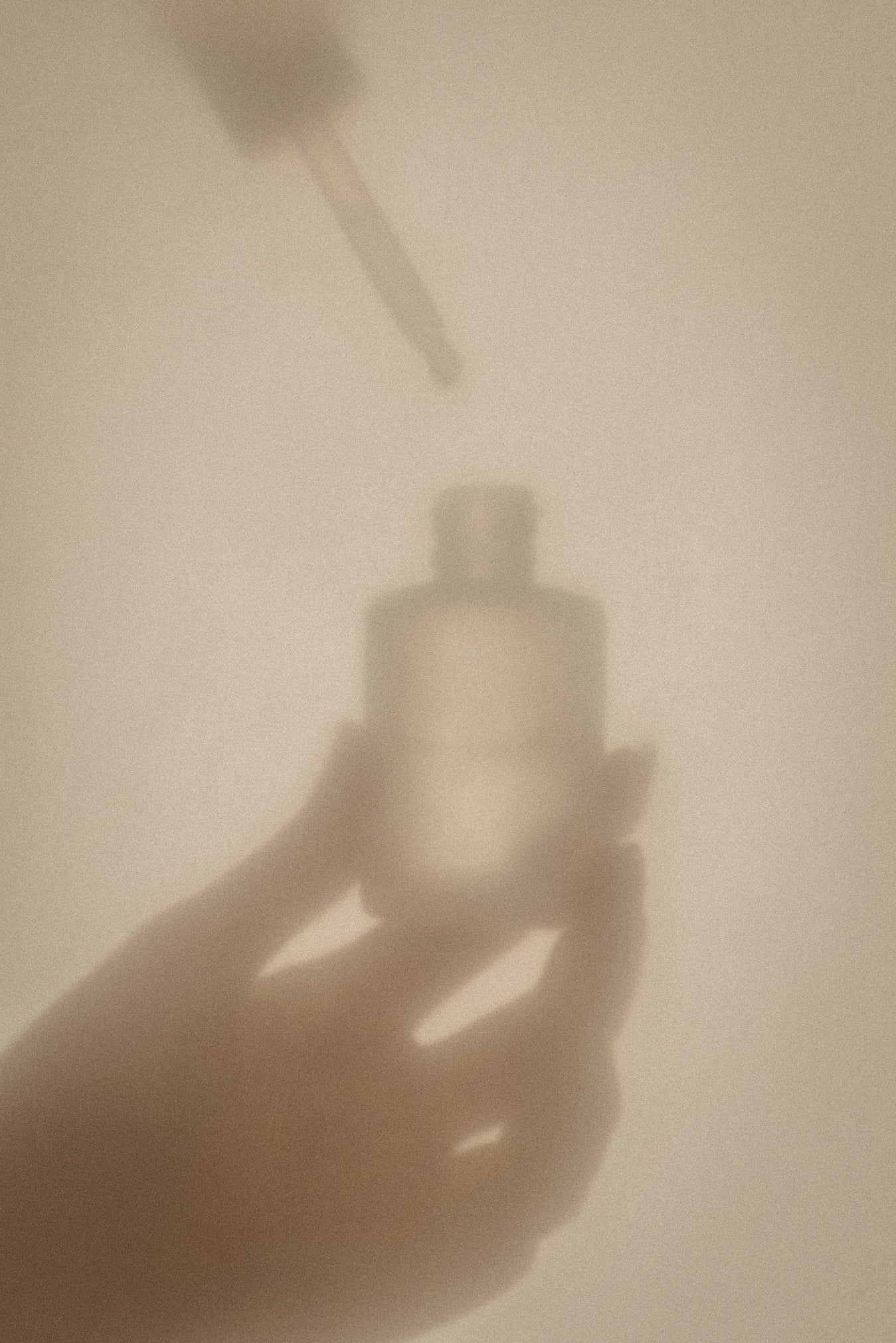 Stimmungsvolle Schattenaufnahme einer Hand mit Glasflakon und Pipette – symbolisiert das feine Duftprofil der Healyni Narbencreme mit ätherischen Ölen