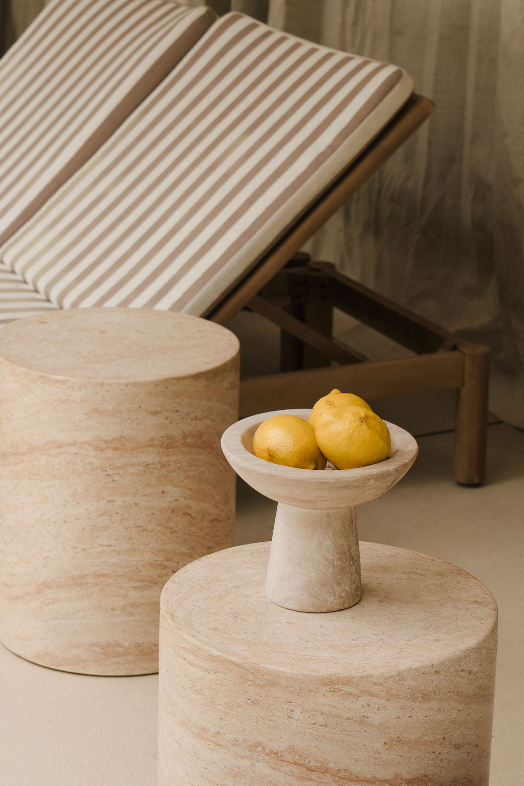 Zitronen in Steinschale auf Naturtisch neben Liegestuhl – mediterrane Spa-Atmosphäre als Symbol für gesunde Entspannung und ganzheitliche Pflege.